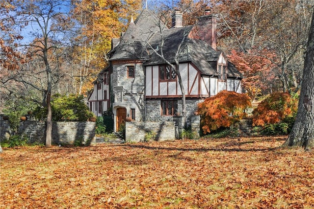 view of front of house featuring stone siding, roof with shingles, a chimney, and stucco siding