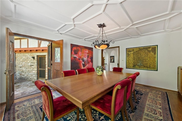 dining space with arched walkways, an inviting chandelier, wood finished floors, coffered ceiling, and baseboards