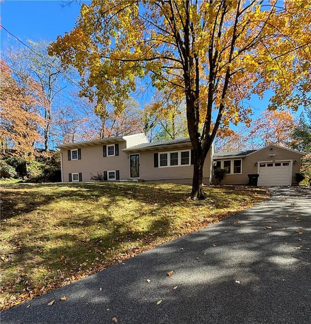 tri-level home featuring a garage and a front lawn