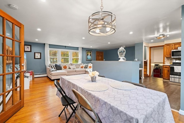 dining room featuring a chandelier, a baseboard radiator, and light hardwood / wood-style flooring