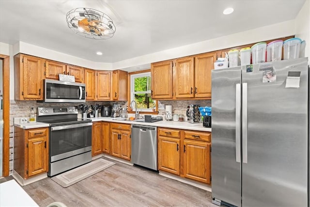 kitchen featuring backsplash, sink, stainless steel appliances, and light hardwood / wood-style floors