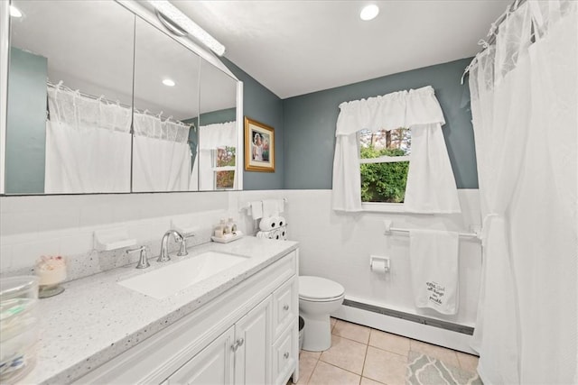 bathroom with a baseboard radiator, tile patterned floors, toilet, vanity, and tile walls