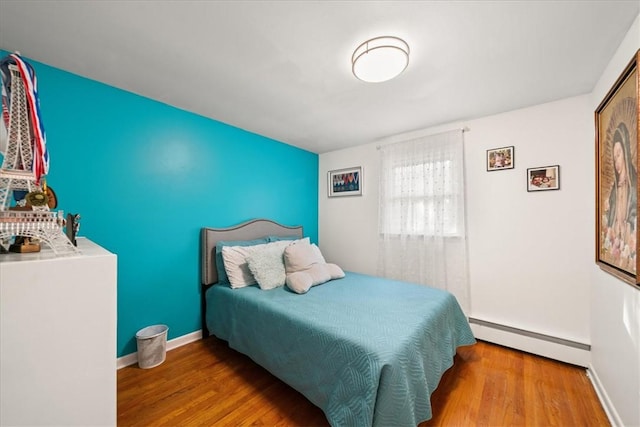 bedroom with hardwood / wood-style flooring and a baseboard heating unit