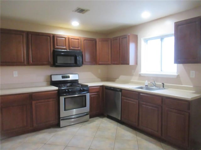 kitchen featuring appliances with stainless steel finishes, light tile patterned floors, and sink