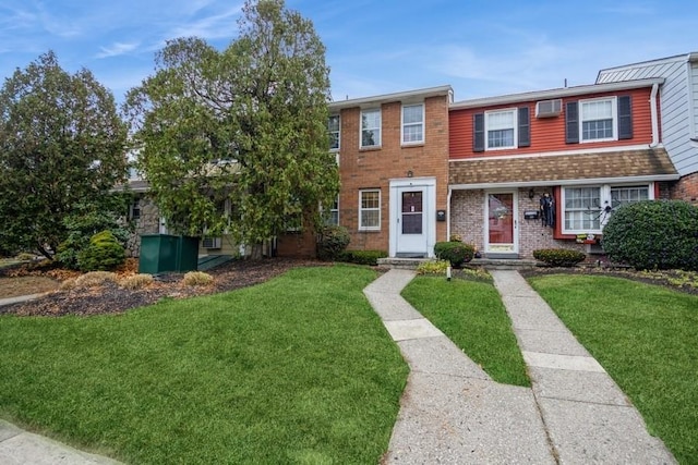 view of property featuring a front yard and a wall mounted AC