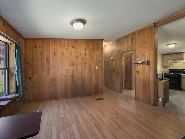 empty room with light wood-type flooring and wooden walls