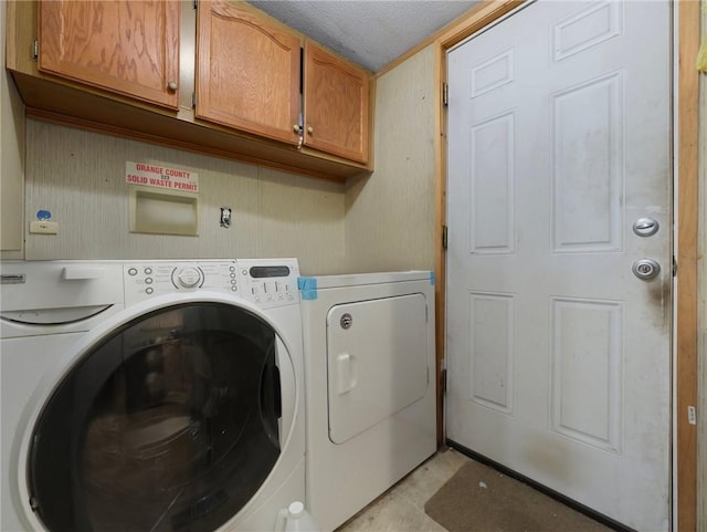 laundry area featuring cabinets, a textured ceiling, and separate washer and dryer