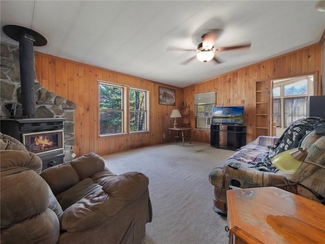 living room featuring light carpet, ceiling fan, a wood stove, lofted ceiling, and wood walls