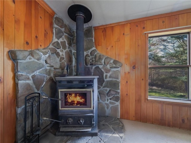 room details featuring carpet flooring, a wood stove, and wooden walls