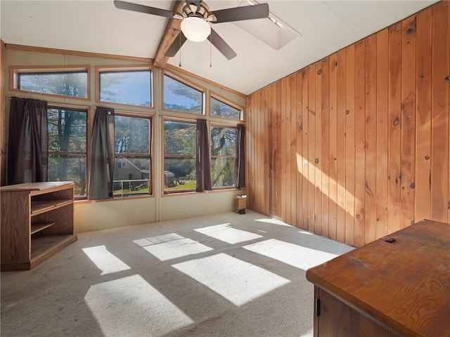 carpeted spare room featuring lofted ceiling with beams, ceiling fan, and wooden walls