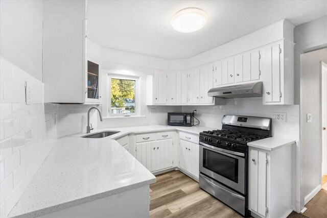 kitchen featuring gas stove, sink, light hardwood / wood-style flooring, extractor fan, and white cabinets