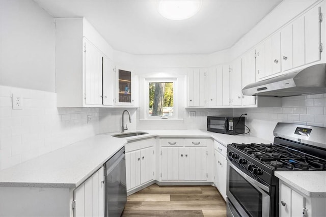 kitchen with sink, decorative backsplash, light wood-type flooring, white cabinetry, and stainless steel appliances