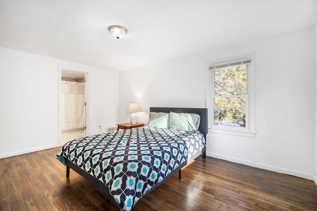 bedroom featuring ensuite bathroom and dark wood-type flooring