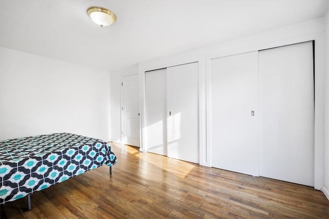 bedroom with hardwood / wood-style floors and multiple closets