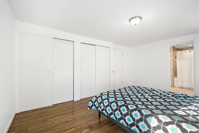 bedroom with ensuite bath, multiple closets, and hardwood / wood-style floors