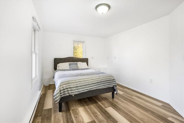 bedroom featuring baseboard heating and hardwood / wood-style floors