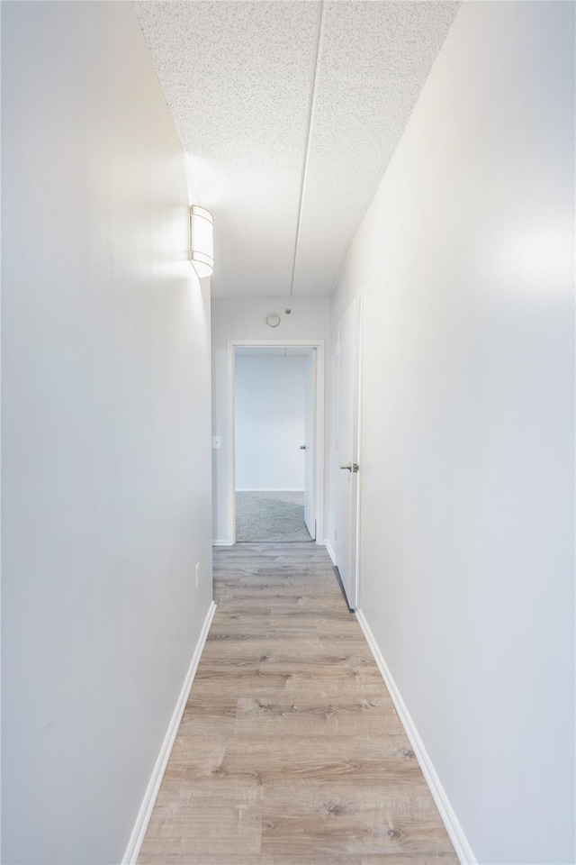 corridor featuring a textured ceiling and light hardwood / wood-style flooring