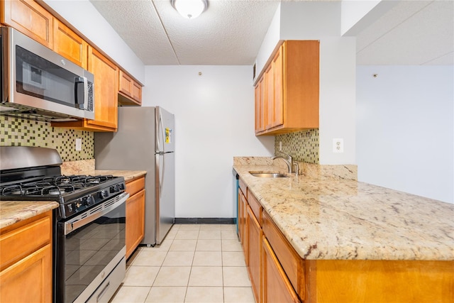 kitchen featuring decorative backsplash, sink, light tile patterned flooring, and appliances with stainless steel finishes