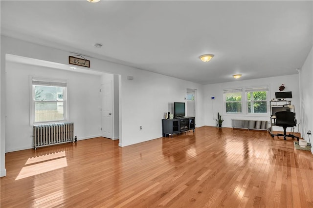 unfurnished living room featuring radiator heating unit and wood-type flooring