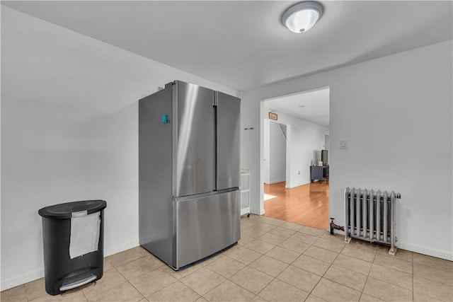 kitchen with stainless steel fridge, light wood-type flooring, and radiator