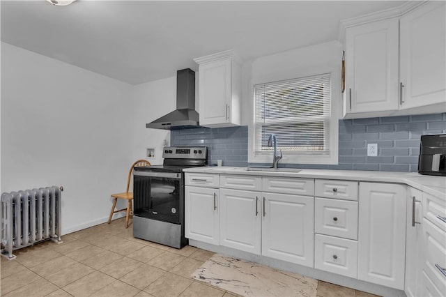 kitchen featuring radiator, stainless steel electric range oven, sink, wall chimney range hood, and white cabinets