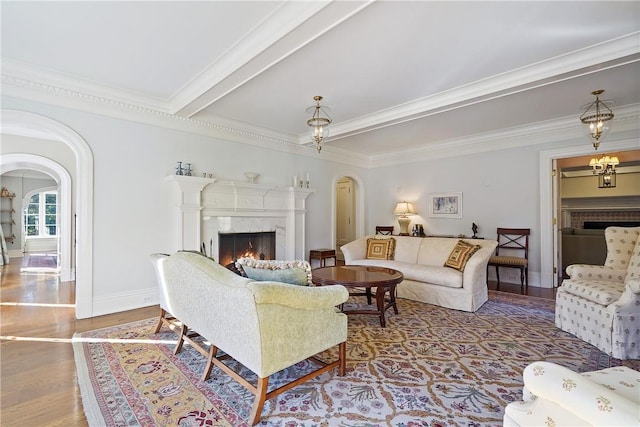 living room featuring beamed ceiling, hardwood / wood-style flooring, crown molding, and a premium fireplace