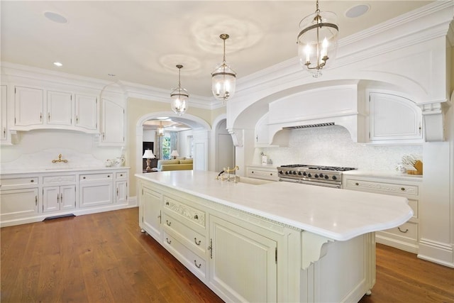 kitchen with crown molding, a center island with sink, dark wood-type flooring, and high end stainless steel range