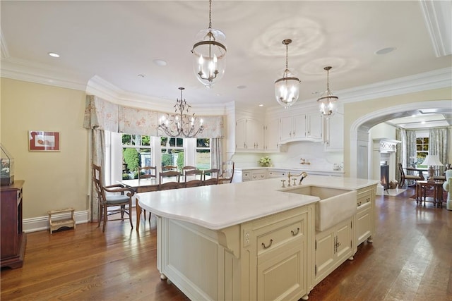 kitchen featuring decorative light fixtures, sink, a kitchen island with sink, and dark wood-type flooring