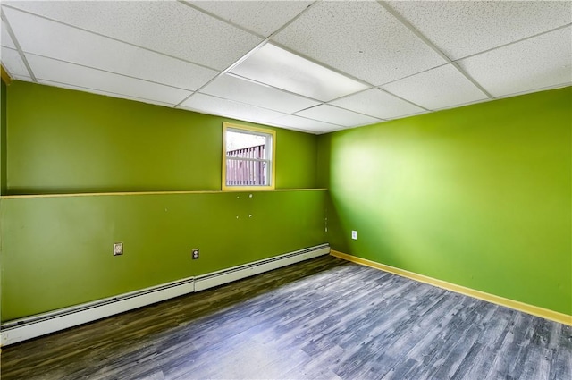 empty room featuring hardwood / wood-style flooring, a drop ceiling, and baseboard heating