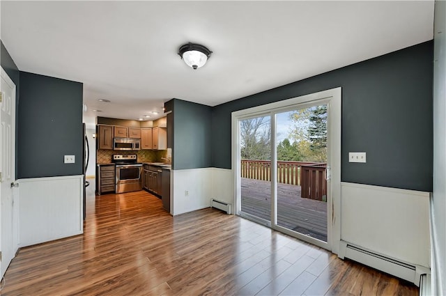 interior space with baseboard heating, tasteful backsplash, hardwood / wood-style floors, and stainless steel appliances