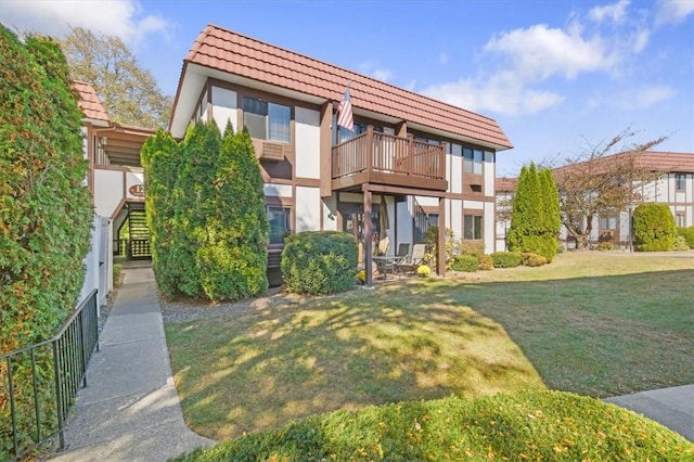 view of front of house with a balcony and a front lawn