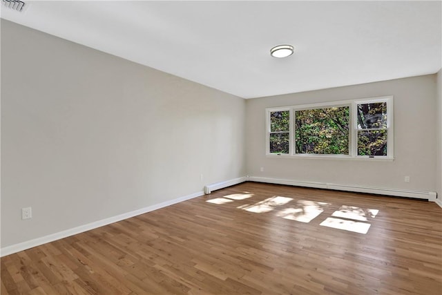 empty room with wood-type flooring and a baseboard heating unit