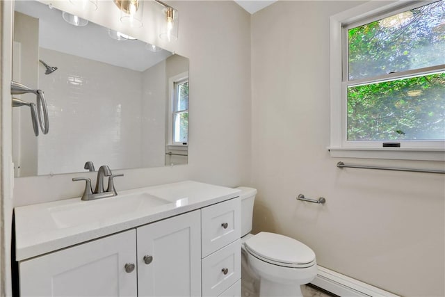 bathroom featuring vanity, toilet, baseboard heating, and a healthy amount of sunlight