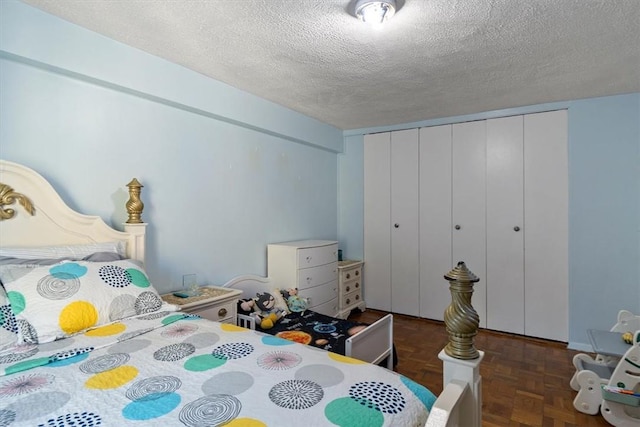 bedroom featuring dark parquet flooring, a textured ceiling, and a closet