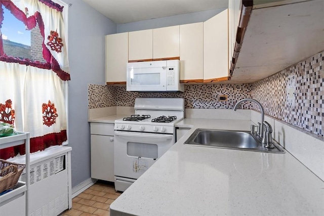 kitchen featuring tasteful backsplash, white cabinetry, sink, and white appliances