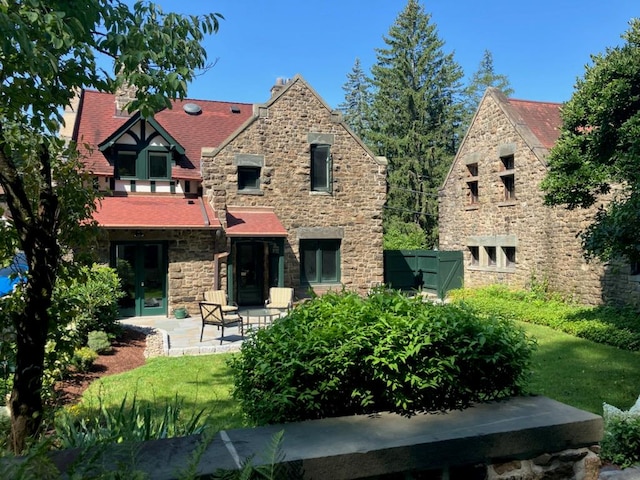 back of house with a patio area and a lawn