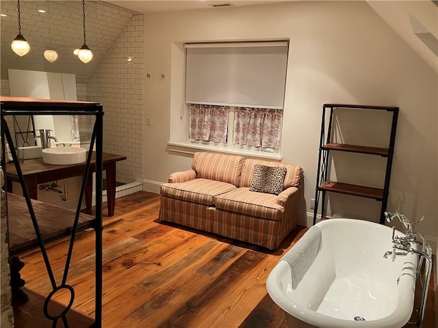 bathroom with lofted ceiling, wood-type flooring, a bathing tub, and a baseboard heating unit