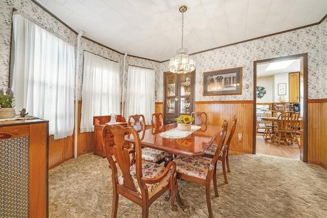 dining room featuring wooden walls, light hardwood / wood-style floors, ornamental molding, and a notable chandelier