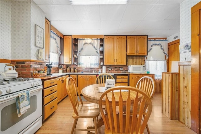 kitchen with light wood-type flooring, white appliances, a drop ceiling, and sink