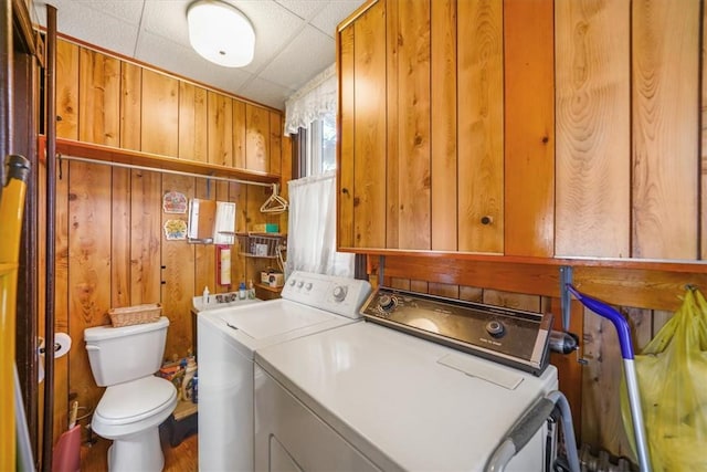 laundry area with wood walls and washer and dryer