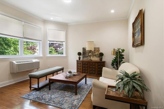 living area featuring an AC wall unit, wood-type flooring, and ornamental molding