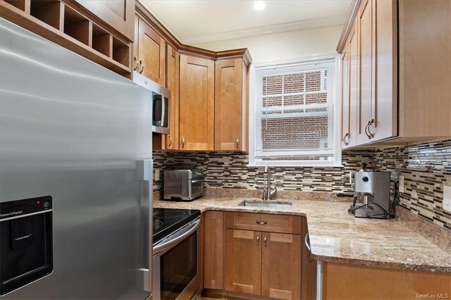 kitchen with light stone countertops, sink, tasteful backsplash, appliances with stainless steel finishes, and ornamental molding