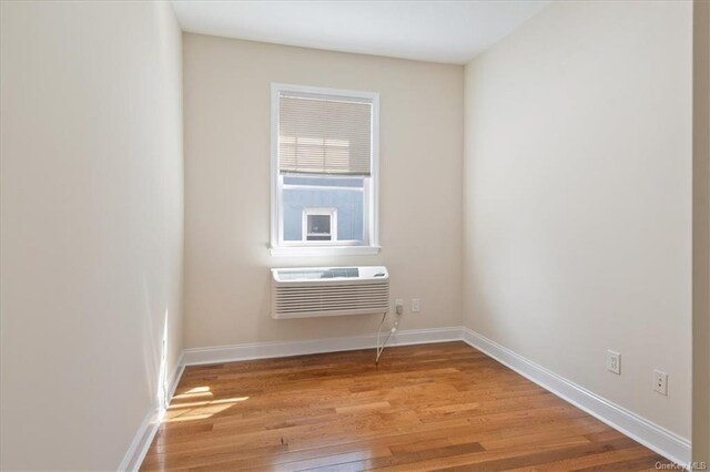 empty room with light wood-type flooring and an AC wall unit