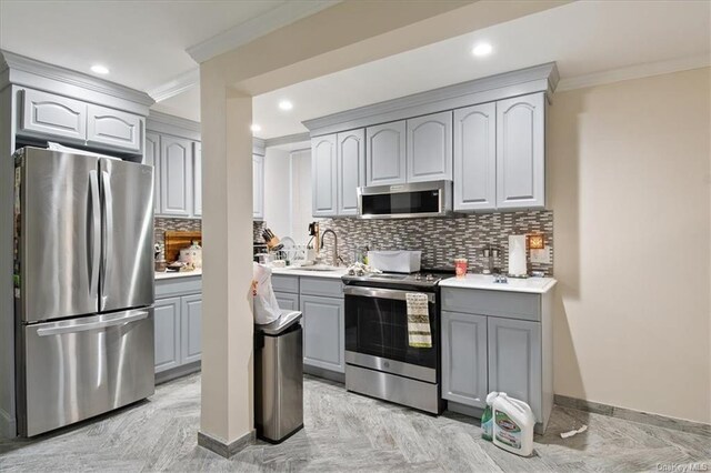 kitchen featuring appliances with stainless steel finishes, tasteful backsplash, ornamental molding, sink, and gray cabinets