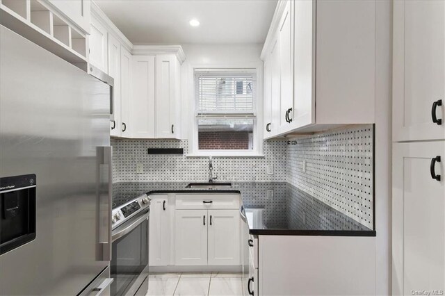 kitchen with backsplash, stainless steel appliances, white cabinetry, and sink