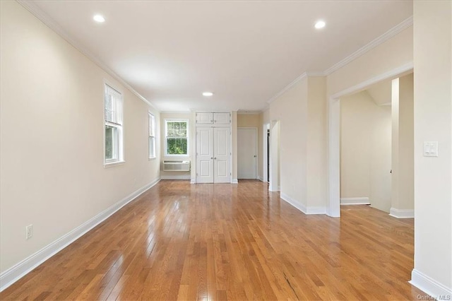 spare room featuring a wall mounted air conditioner, light wood-type flooring, and ornamental molding