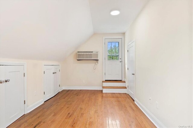 bonus room with lofted ceiling, light hardwood / wood-style flooring, and a wall mounted AC