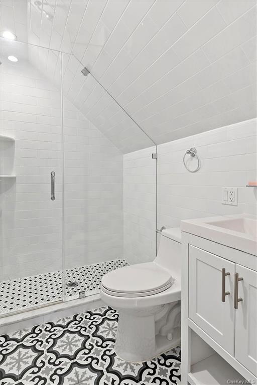 bathroom featuring tile patterned floors, lofted ceiling, toilet, a shower with door, and vanity