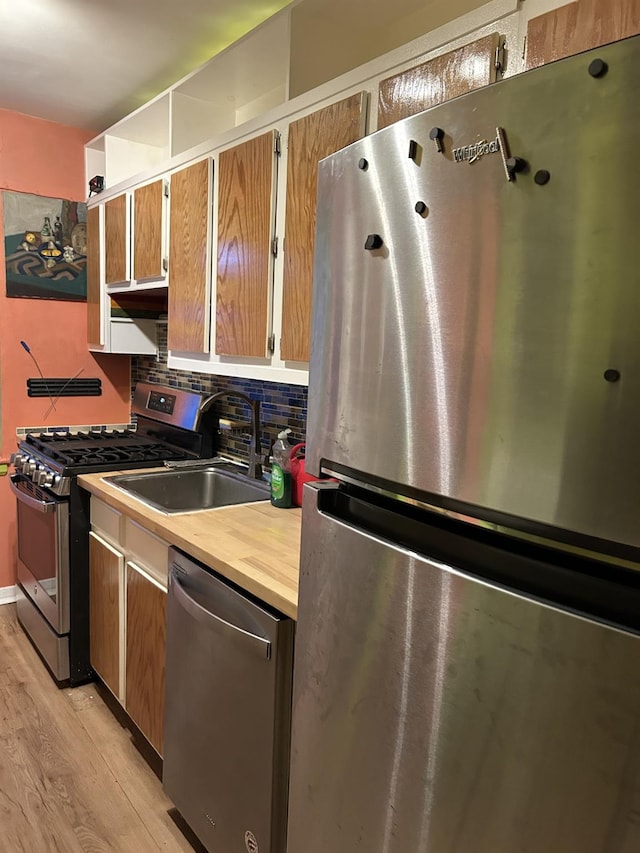 kitchen with decorative backsplash, light hardwood / wood-style floors, sink, and stainless steel appliances