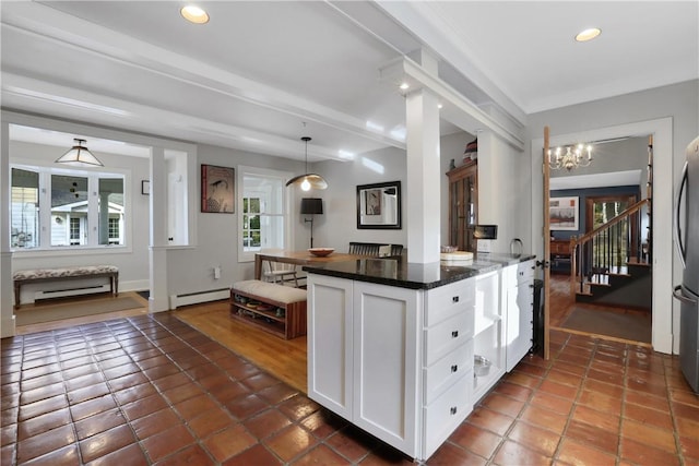 kitchen with decorative light fixtures, white cabinets, dark stone countertops, a baseboard heating unit, and stainless steel refrigerator